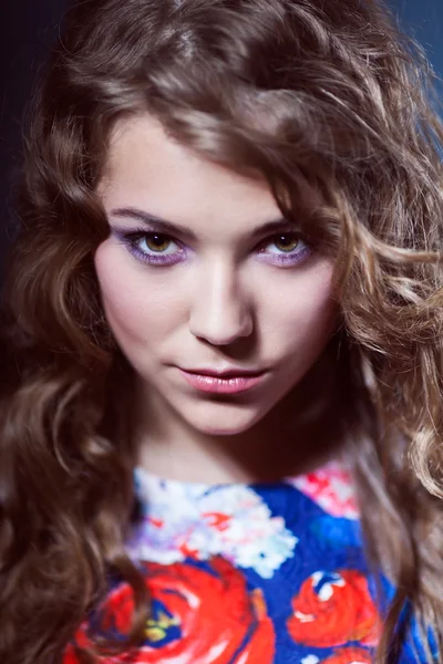 Portrait d'une belle jeune fille avec un sourire doux avec des dents dans une robe bleue avec des fleurs rouges avec de longs cheveux naturels et le maquillage — Photo