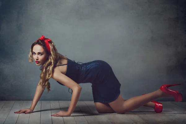 Seksi sarışın kadın kot sundress ve kırmızı ayakkabı kız retro kadın seksi bacaklar ve kırmızı capitium katta oturan yerde sürünerek kafasında pin ve saç düzeltiyor — Stok fotoğraf