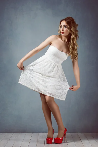 Sexy beautiful blond girl with makeup in a white short dress with long legs in red high heels Pin up girl, retro woman, sexy legs surprised, scared — Stock Photo, Image