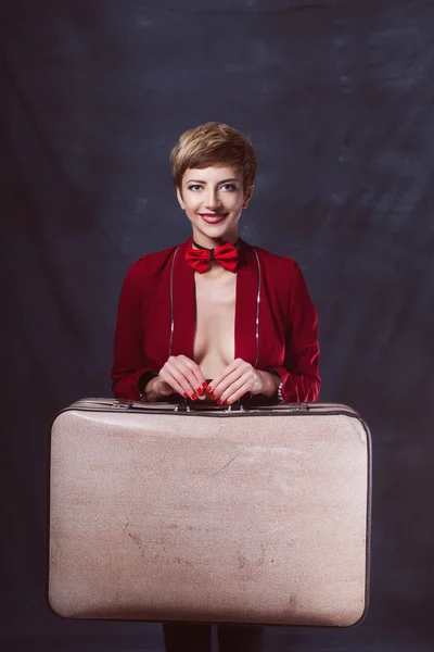 Young sexy girl with a suitcase in a jacket and pants in bow tie with makeup movement is in a hurry — Stock Photo, Image