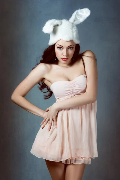 長い絹のような髪、ピンクのドレス悪いウサギ セクシーな sly プレイ少年男性のためのウサギのイメージで女の子のポーズで美しいセクシーな女性 — ストック写真