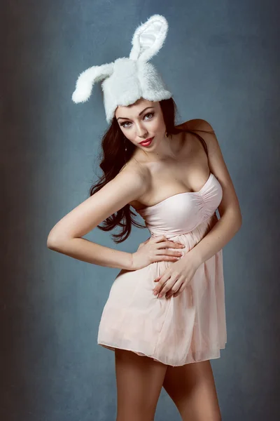 Piękna sexy kobieta z długie jedwabiste włosy, pozowanie, dziewczyna na obrazku królika w różowej sukience złe bunny chytry sexy wygląd grać chłopiec dla mężczyzn — Zdjęcie stockowe