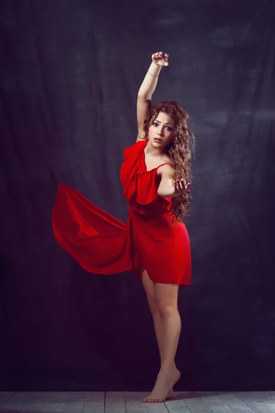 Young beautiful and charming girl in red is dancing with a slender figure plastic body dancer with hair gymnast performs twine curly ringlet — Stock Photo, Image