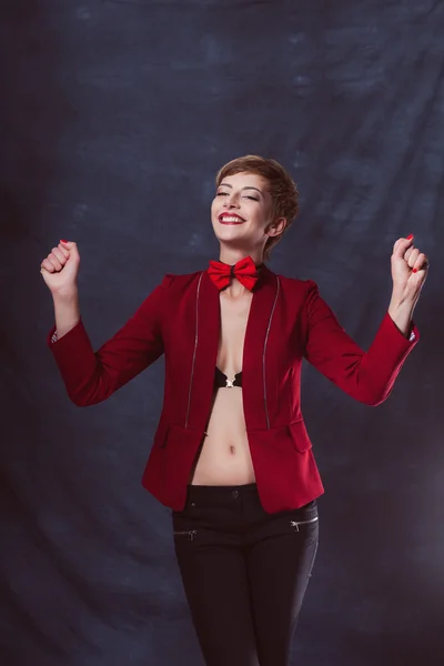 Portrait of a beautiful business woman reached victory or vyigrasha holding hands in fists first place in the red jacket and bow tie chest Smile and teeth — Stock Photo, Image