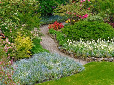 Yürüme yolları ve çiçeklerle kaplı çiçek tarhları olan bahar bahçesi.