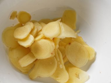 Turşuya hazırlanmak için zencefil kökü mandolinle dilimleniyor.