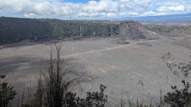 Mavi gökyüzünün altında geniş bir volkanik krater manzarası.