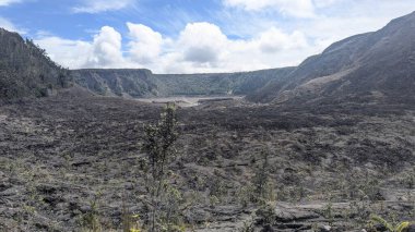 Parlak mavi bir gökyüzünün altında engin bir volkanik manzara.