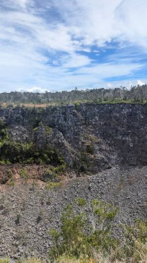 Berrak mavi gökyüzünün altındaki engebeli volkanik manzara