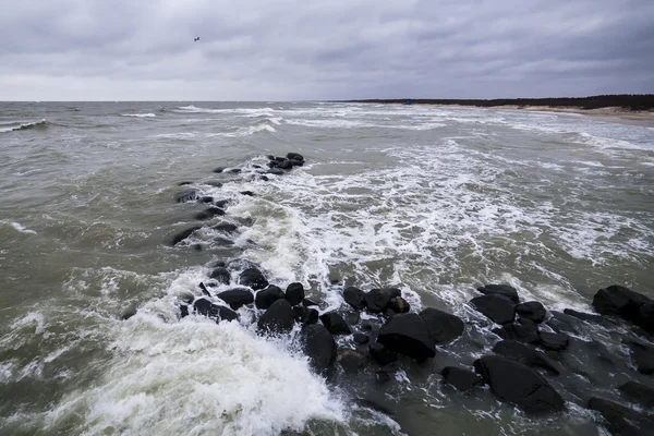 Fale na klifie na plaży, plaża kamienista. — Zdjęcie stockowe