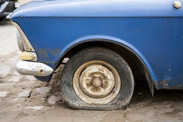 Oude auto met zichtbare lekke band. Rechtenvrije Stockafbeeldingen