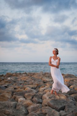Bir taş iskele th karşı beyaz elbise maliyetlerinde genç kız