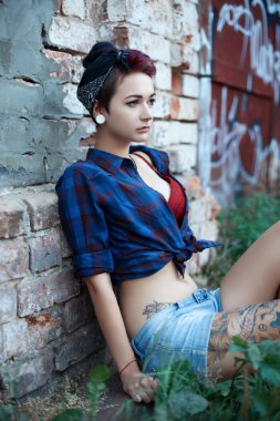 Emo kız pin-up bir tuğla duvara yakın oturur