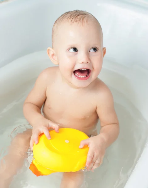 Smiling baby bathes in a bath with a rubber toy — Stock Photo, Image