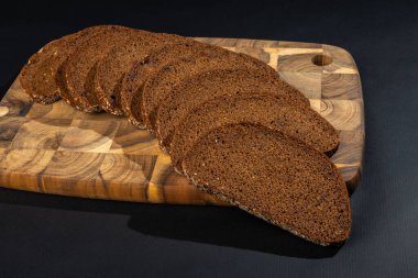 Tahtada dilimlenmiş çavdar ekmeği ve siyah bir arka plan.