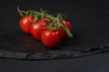 Siyah arka planda küçük domatesler.