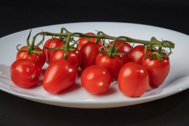 Siyah arka planda küçük domatesler.