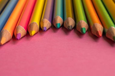 Pembe arka planda renkli kalemler