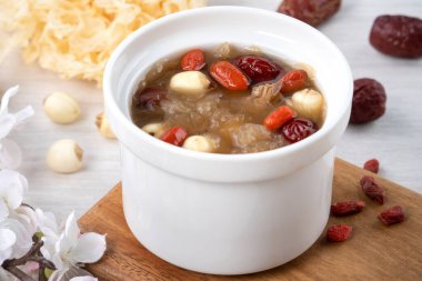 Beyaz zemin üzerinde nilüfer tohumu, kırmızı hurma (jujube) ve kurt üzümü (goji, gojiberry) bulunan geleneksel Çin pamuk beyaz mantar çorbasını kapatın..