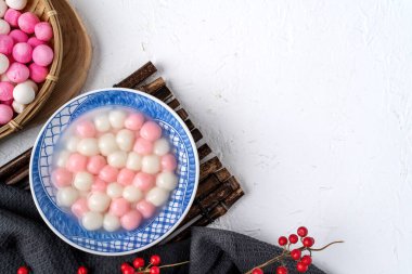 Kırmızı ve beyaz tangyuan 'ın (tang yuan, glutinous rice dumpling balls) beyaz arka planda kış gündönümü festivali yemekleri için mavi kasede.