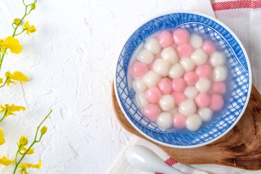 Kırmızı ve beyaz tangyuan 'ın (tang yuan, glutinous rice dumpling balls) beyaz arka planda kış gündönümü festivali yemekleri için mavi kasede.