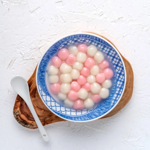Kırmızı ve beyaz tangyuan 'ın (tang yuan, glutinous rice dumpling balls) beyaz arka planda kış gündönümü festivali yemekleri için mavi kasede.