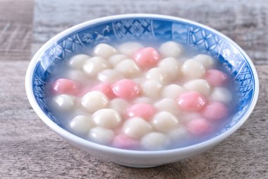 Kırmızı ve beyaz tangyuan 'ı (tang yuan, glutinous rice dumpling balls) kış gündönümü festivali için ahşap zemin üzerinde mavi kasede kapatın..