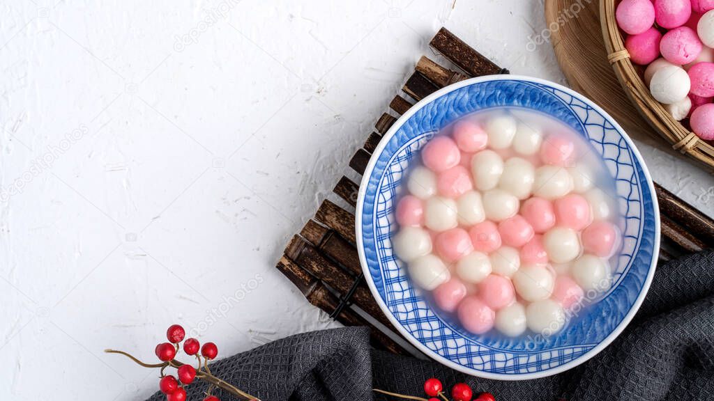 Top view of red and white tangyuan (tang yuan, glutinous rice dumpling balls) in blue bowl on white background for Winter solstice festival food.