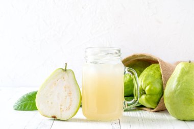 Taze meyve suyu setiyle nefis guava meyvesi. Parlak beyaz tahta masa arka planında izole edilmiş. Yakın plan..