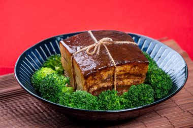 Dong Po Rou (Dongpo pork meat) in a beautiful blue plate with green broccoli vegetable, traditional festive food for Chinese new year cuisine meal, close up. clipart