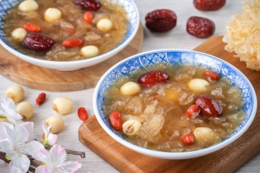 Beyaz zemin üzerinde nilüfer tohumu, kırmızı hurma (jujube) ve kurt üzümü (goji berry, gojiberry) içeren geleneksel Çin pamuk beyaz mantar çorbasını kapatın..