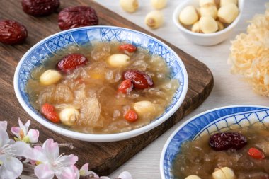 Beyaz zemin üzerinde nilüfer tohumu, kırmızı hurma (jujube) ve kurt üzümü (goji berry, gojiberry) içeren geleneksel Çin pamuk beyaz mantar çorbasını kapatın..