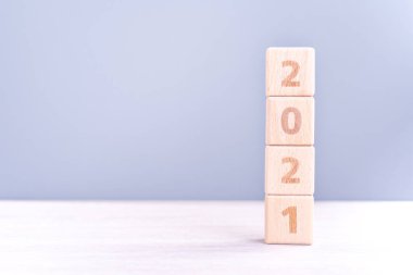 2021 Yeni Yıl Soyut Tasarım Konsepti - Ahşap masa üzerinde izole edilmiş tahta blok küpleri ve açık mavi arka plan.