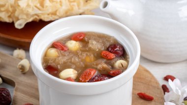 Beyaz zemin üzerinde nilüfer tohumu, kırmızı hurma (jujube) ve kurt üzümü (goji berry, gojiberry) içeren geleneksel Çin pamuk beyaz mantar çorbasını kapatın..