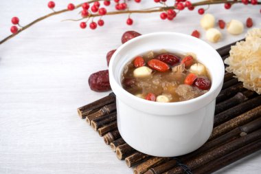 Beyaz zemin üzerinde nilüfer tohumu, kırmızı hurma (jujube) ve kurt üzümü (goji berry, gojiberry) içeren geleneksel Çin pamuk beyaz mantar çorbasını kapatın..