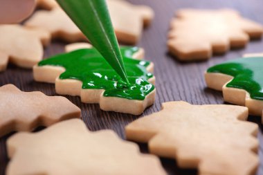 Yeşil kremalı ahşap masa arkasına zencefilli Noel ağacı şekeri çiz. Bayram kutlaması kavramı..