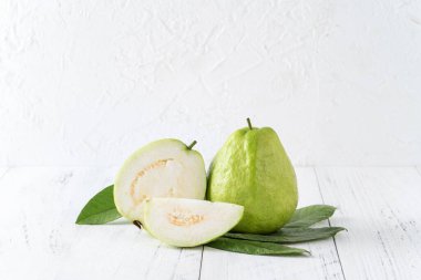 Taze yapraklı nefis guava seti, parlak beyaz ahşap masa arka planında izole edilmiş, yakın plan..