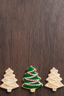 Yeşil kremalı ahşap masa arkasına zencefilli Noel ağacı şekeri çiz. Bayram kutlaması kavramı..