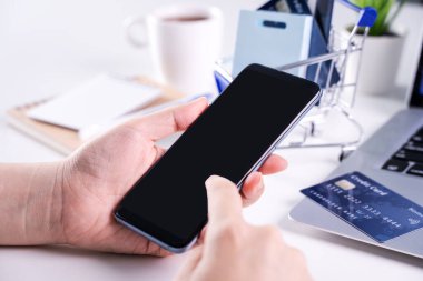 Akıllı cep telefonu kullanan bir kadın evde elektronik ödeme yapıyor.