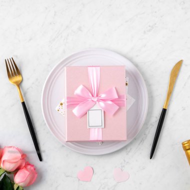 Sevgililer Günü özel yemek konsepti için beyaz tabak ve mermer masa arkasında pembe gül çiçeği..