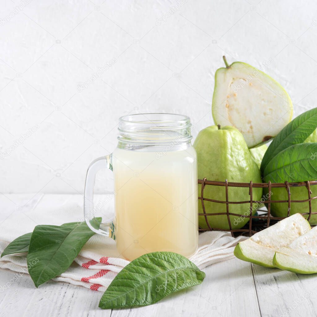 Delicious beautiful guava fruit with fresh juice set isolated on bright white wooden table background, close up.