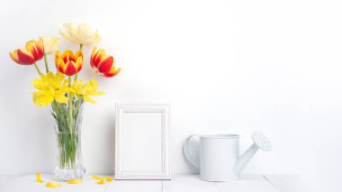 Beyaz duvarında resim çerçevesi olan cam vazoda lale çiçeği, Anneler Günü dekor konsepti..