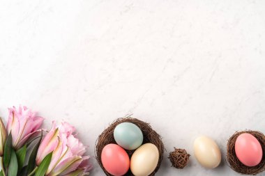 Yuvada renkli Paskalya yumurtaları Pembe zambak çiçekli parlak mermer masa arkaplanı.