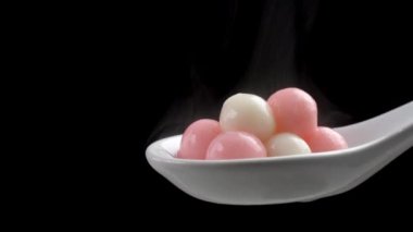 Siyah arka planda beyaz kaşıkta taze ve sıcak Tangyuan pirinç köftesi..
