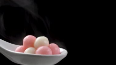 Siyah arka planda beyaz kaşıkta taze ve sıcak Tangyuan pirinç köftesi..