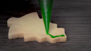 Noel ağacı şekeri kurabiyelerini ahşap masa arkasına kremalı çizmeye yakın..