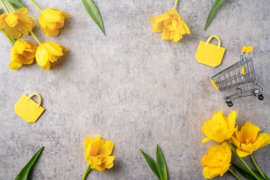 Anneler günü hediye alışverişi kavramı. Gri arkaplanda sarı lale çiçeği buketi tasarımı.