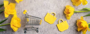 Anneler günü hediye alışverişi kavramı. Gri arkaplanda sarı lale çiçeği buketi tasarımı.