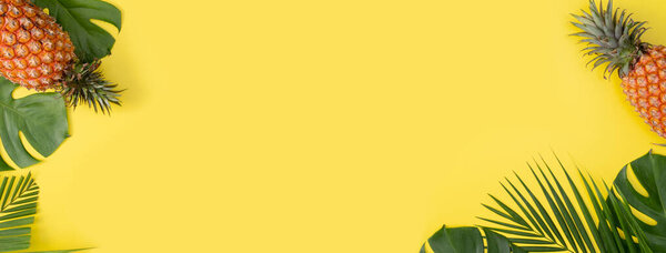 Вид сверху свежего соснового яблока с пальмами и листьями чудовища на желтом фоне стола.
