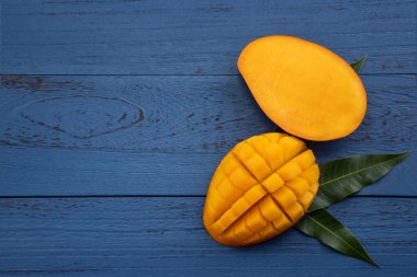 Mavi masa arkaplanının üzerinde dilimlenmiş parçalar olan güzel tropikal meyve tasarımı konsepti.